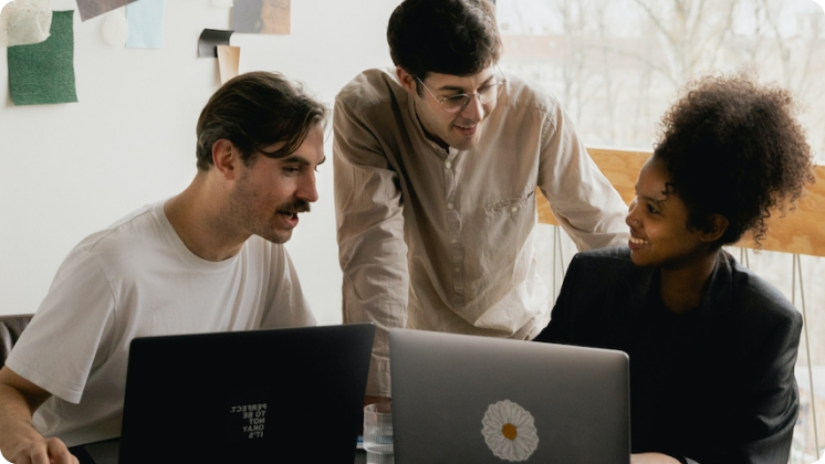 Closeup of three young professionals working together in front of their laptops.